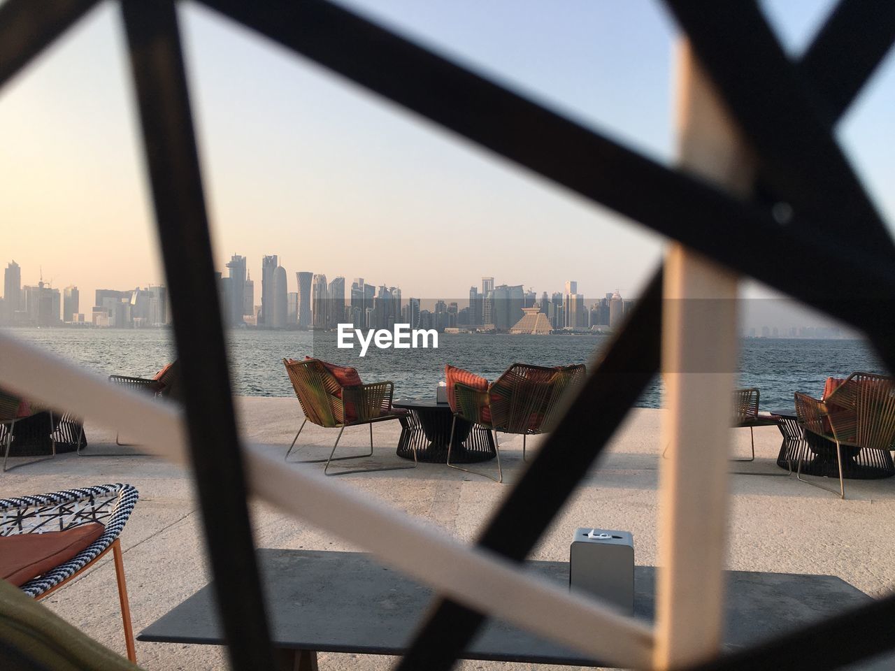 VIEW OF CITYSCAPE AGAINST RIVER SEEN THROUGH FENCE