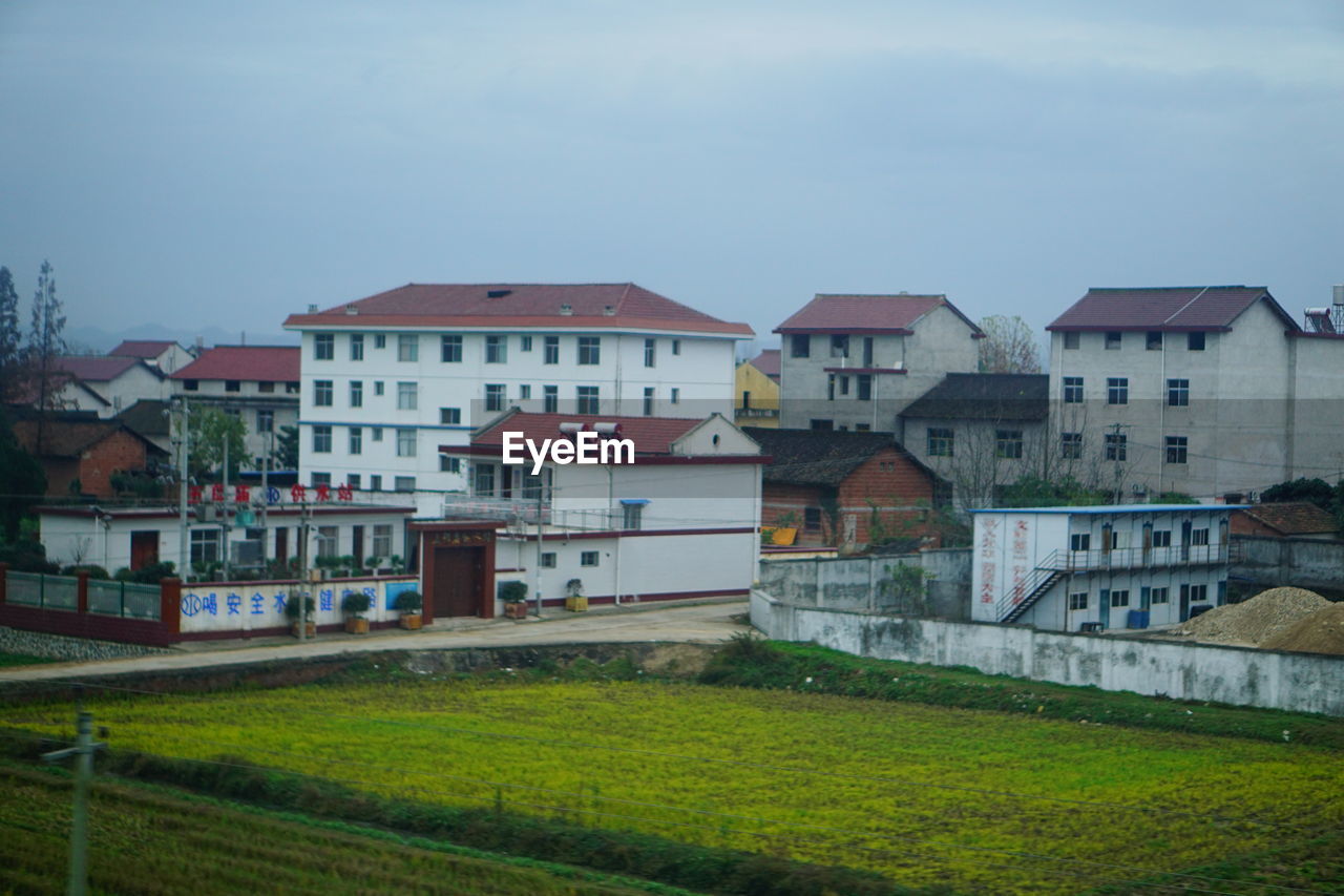 HOUSES BY BUILDINGS AGAINST SKY