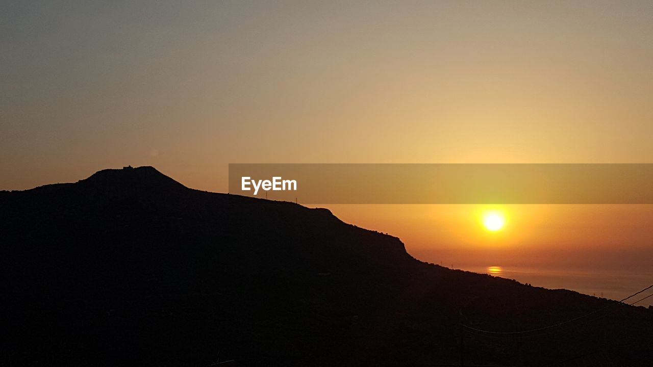 Scenic view of silhouette mountains against clear sky during sunset