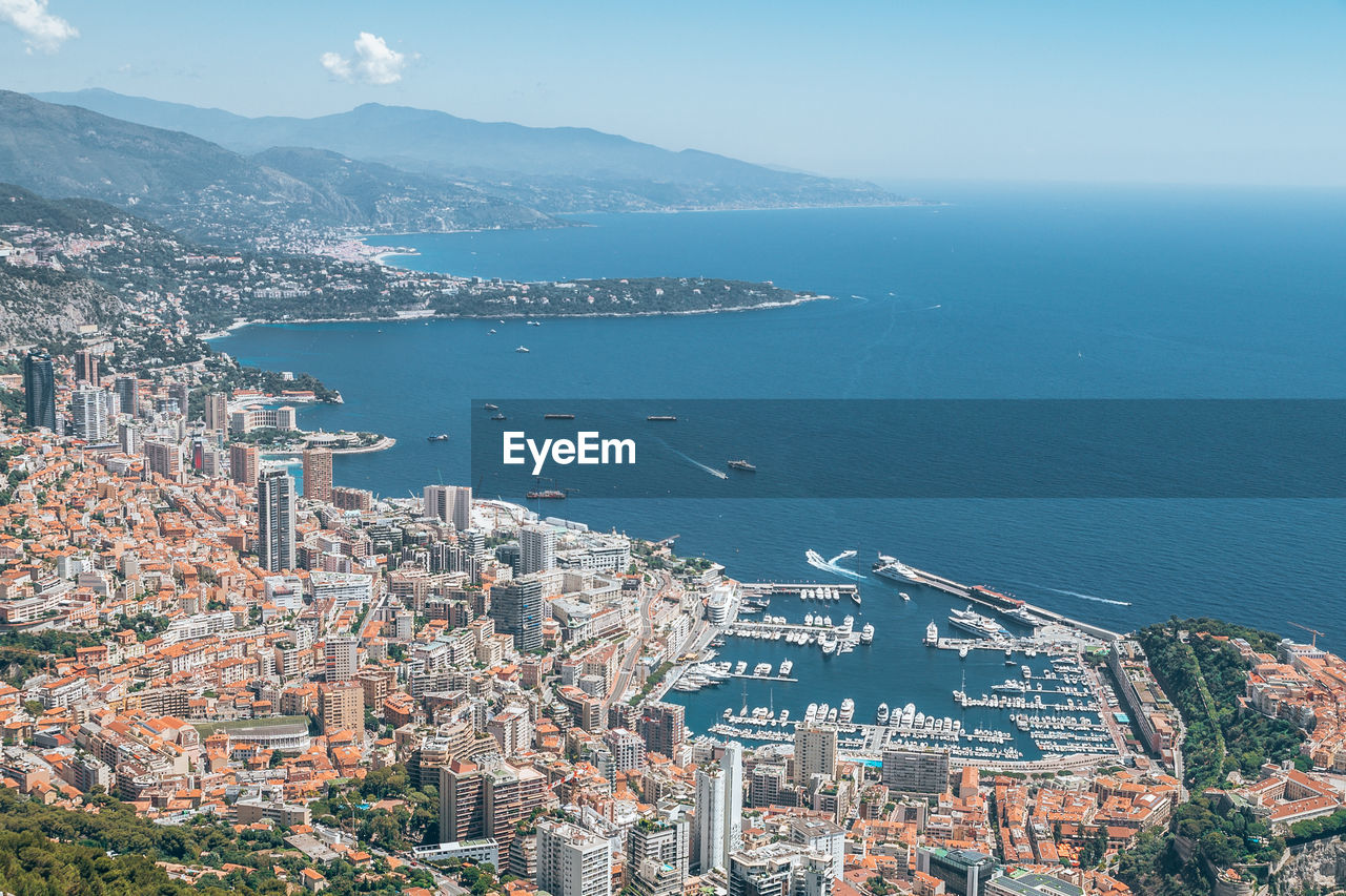 Aerial view of sea by city against sky