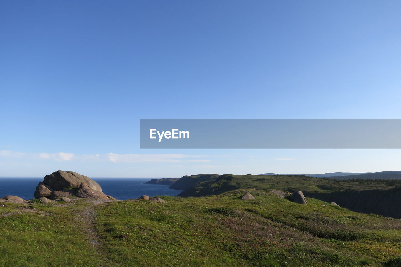 Scenic view of rocks by sea against blue sky