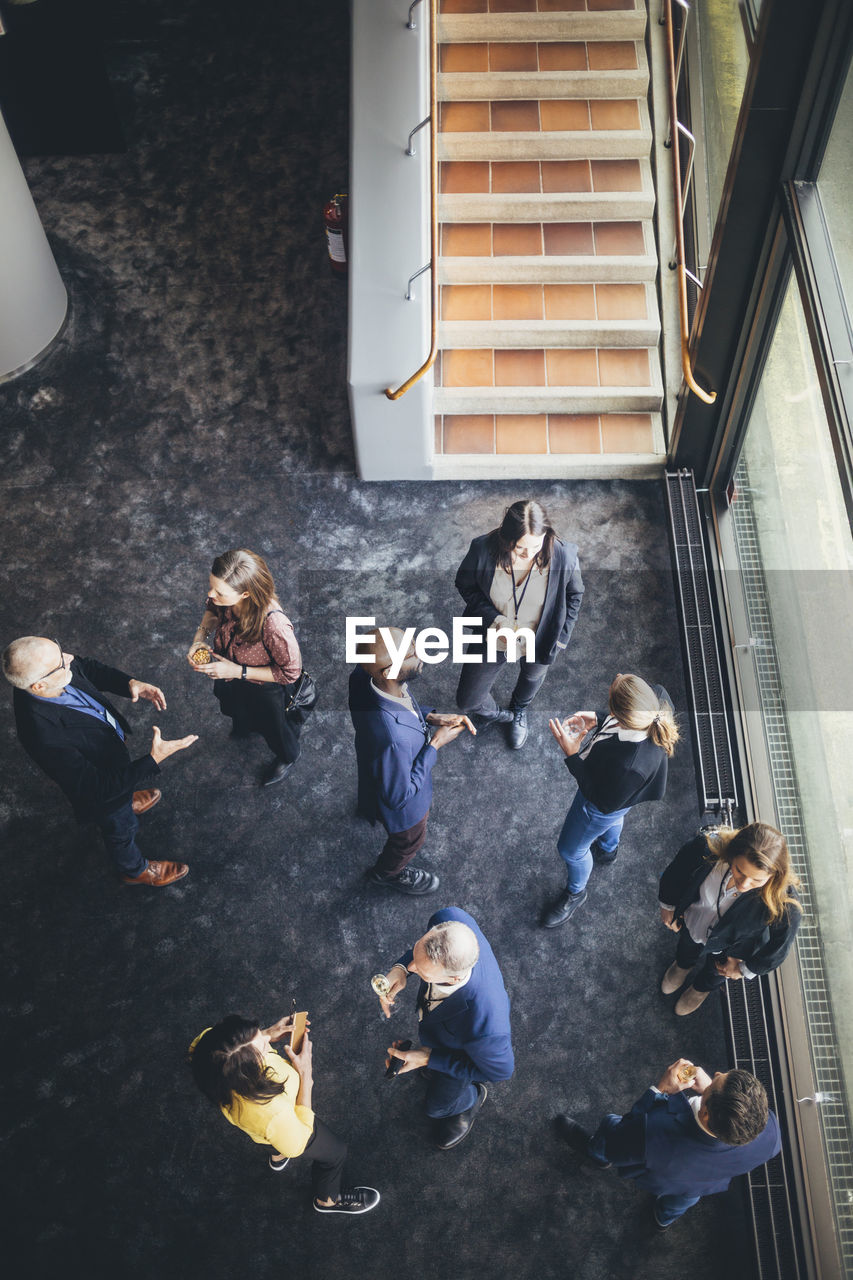 High angle view of business people discussing while standing at workplace