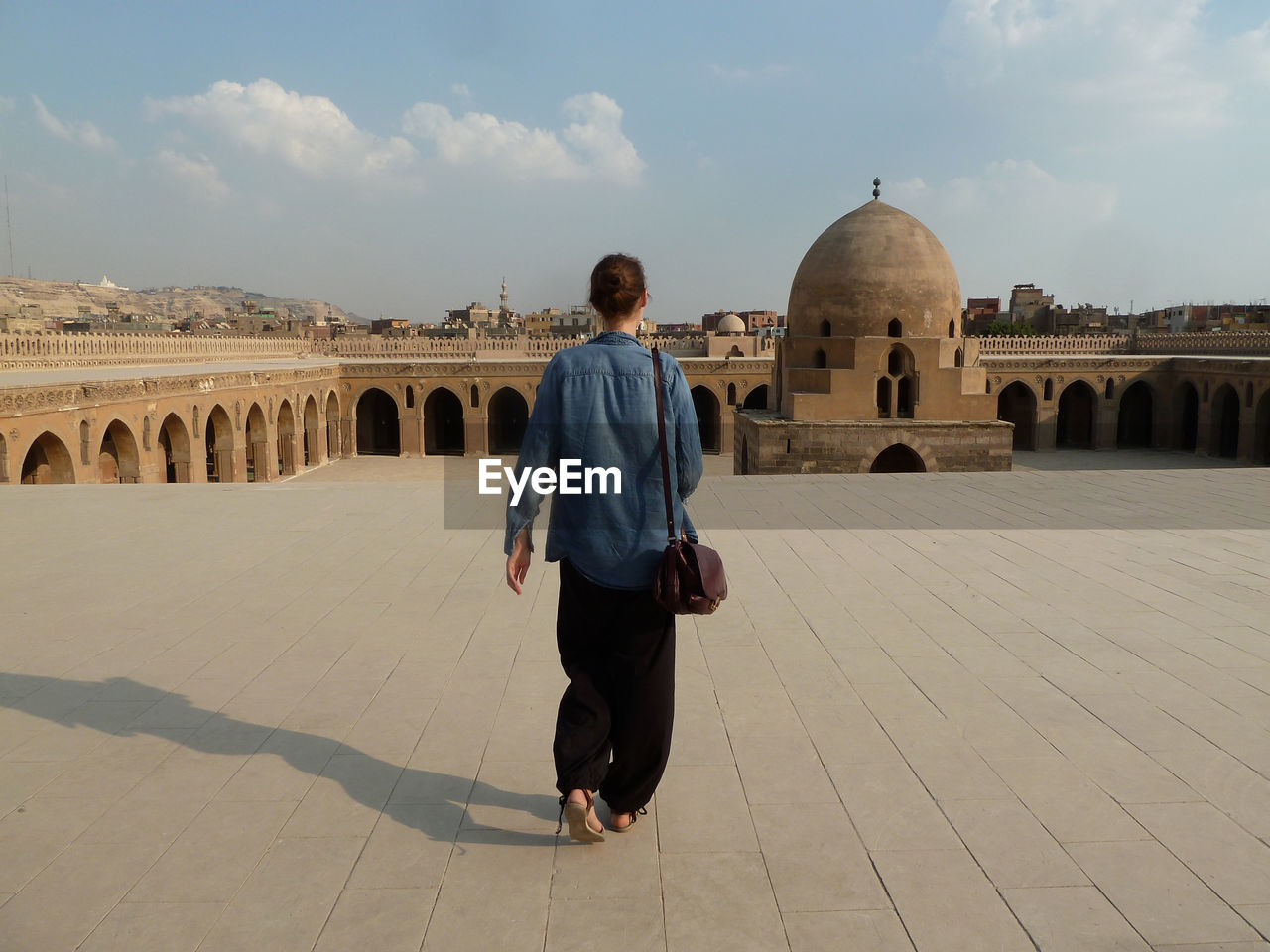 Rear view of tourist walking at mosque of ibn tulun against sky