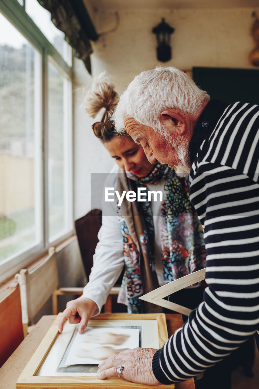 Senior man and woman examining painting at home