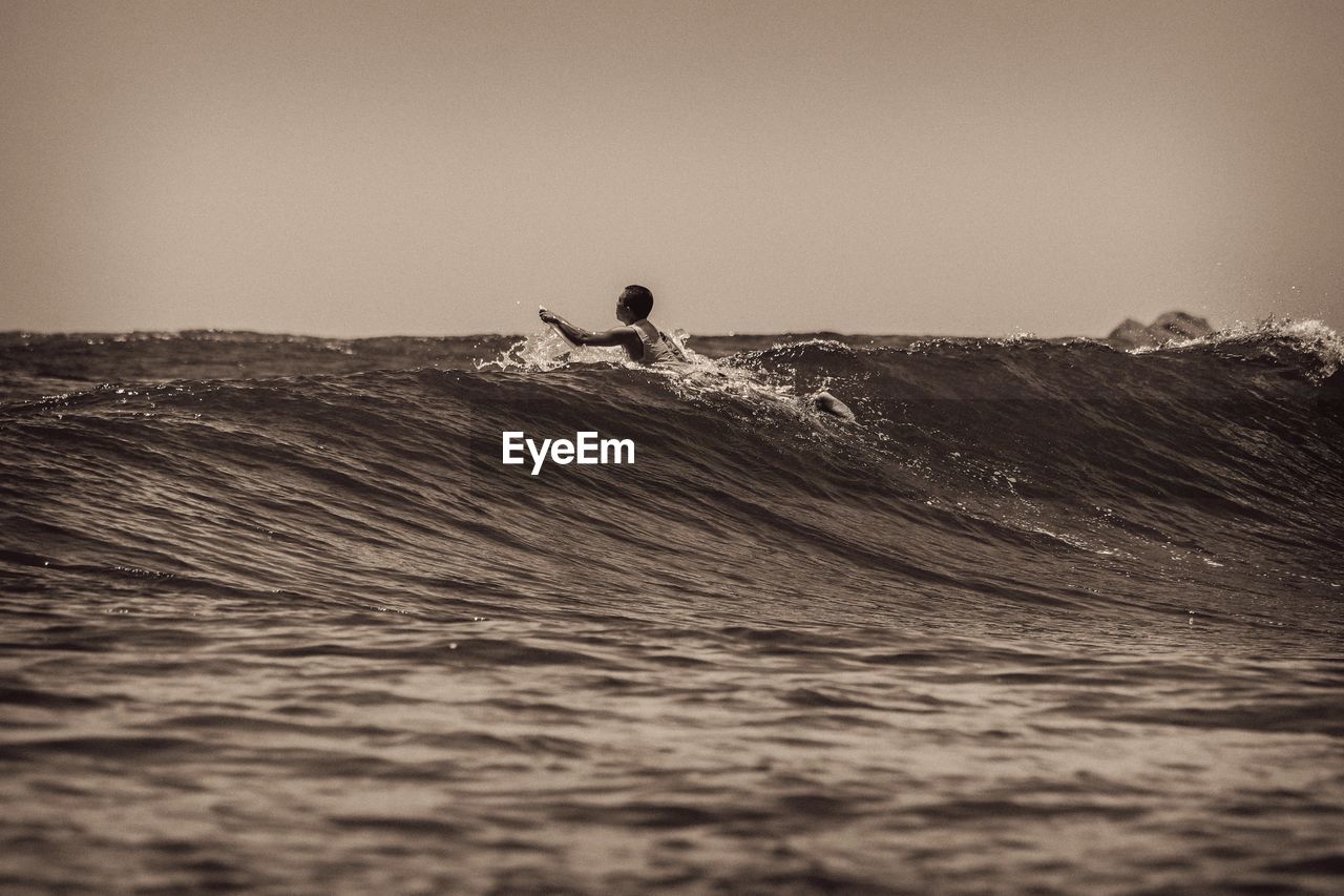 Man surfing in sea against clear sky