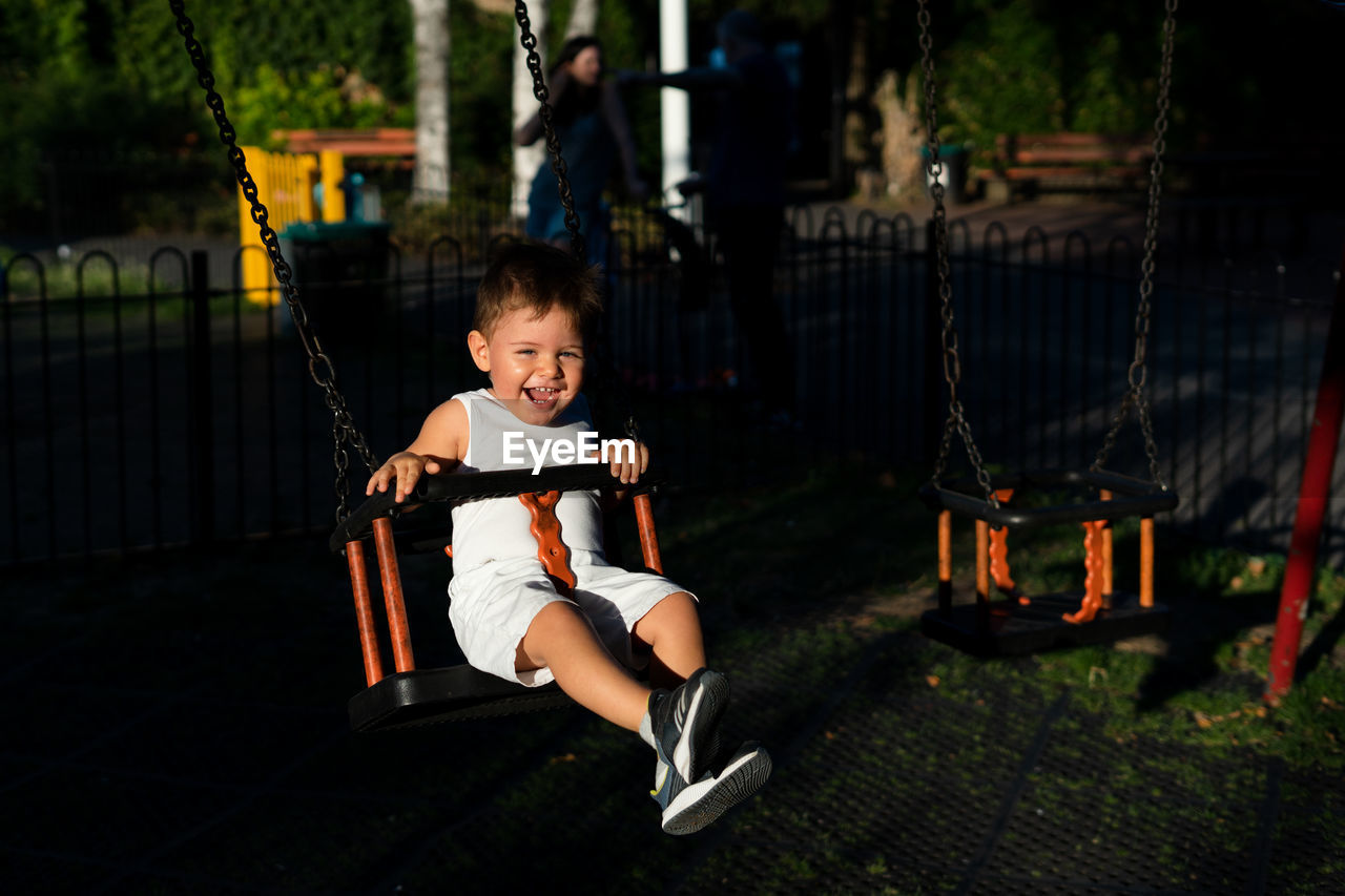 Portrait of smiling girl swinging in playground