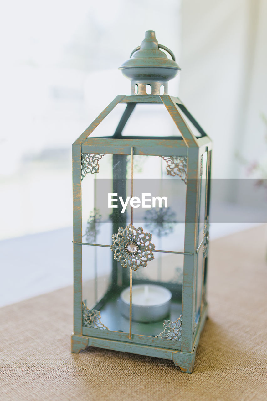 Close-up of lantern on table against window