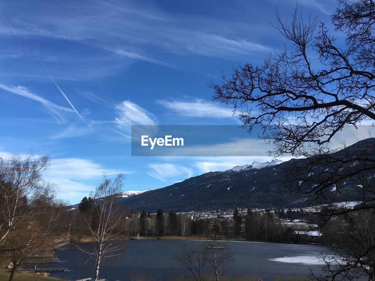 BARE TREES ON SNOWCAPPED MOUNTAINS AGAINST SKY