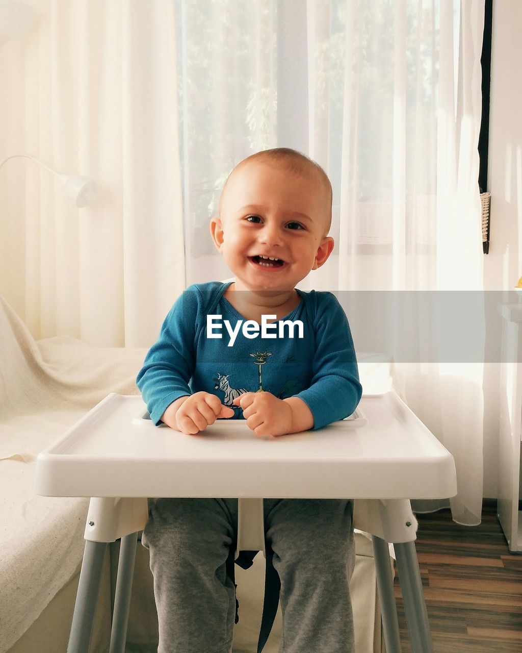 Cheerful baby sitting on high chair at home