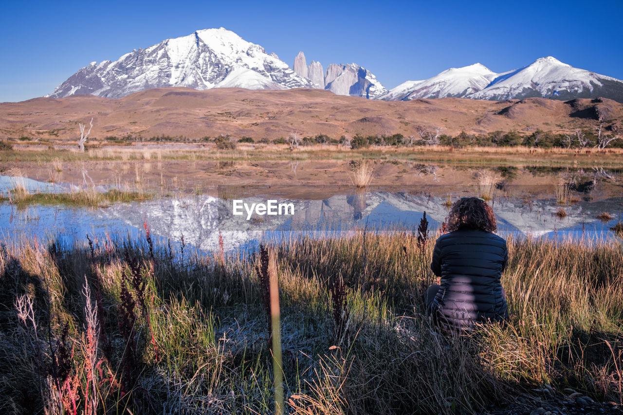 REAR VIEW OF MAN STANDING ON MOUNTAIN