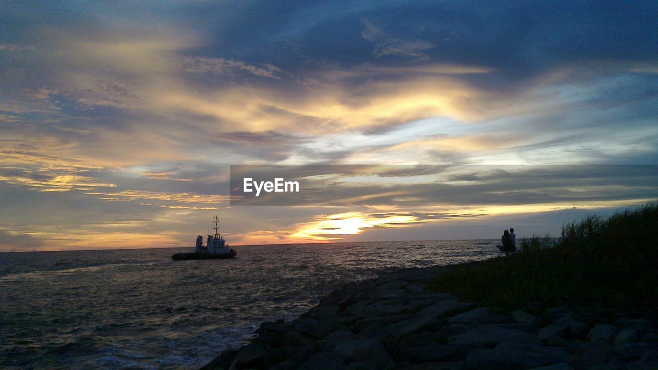 CALM SEA AGAINST DRAMATIC SKY DURING SUNSET