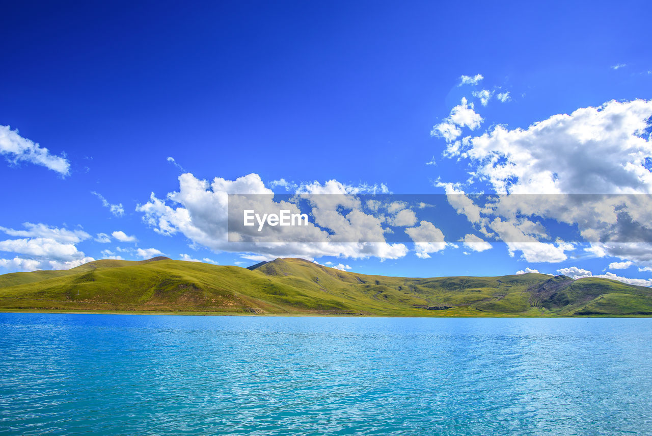 Scenic view of lake and mountains against blue sky