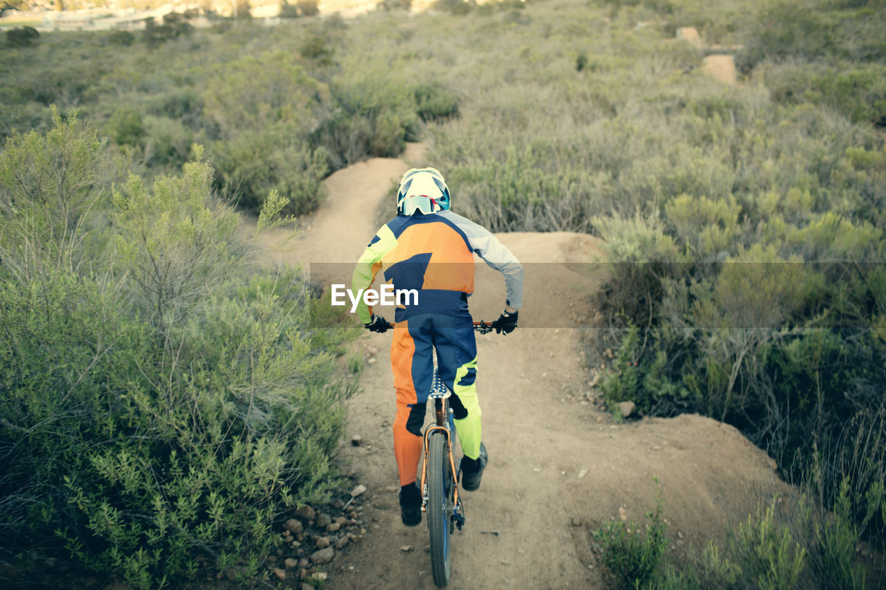 Rear view of biker riding mountain bike on landscape