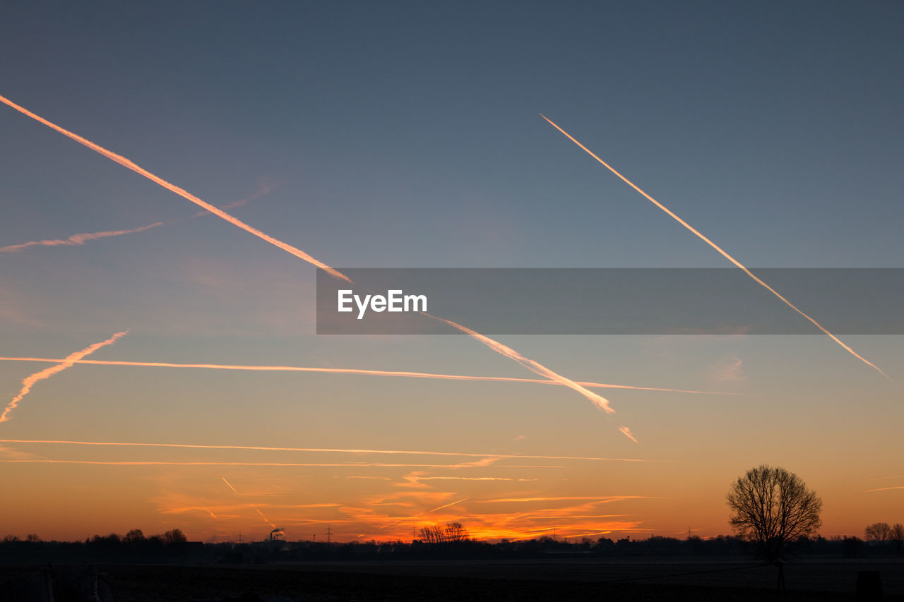 Scenic view of vapor trails in sky at sunset