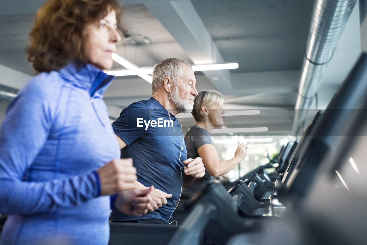 Group of fit seniors on treadmills working out in gym