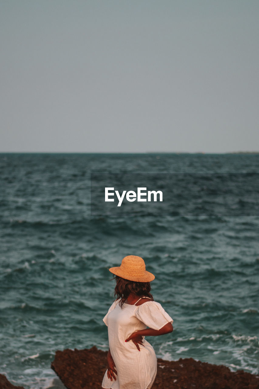 Rear view of woman looking at sea against clear sky