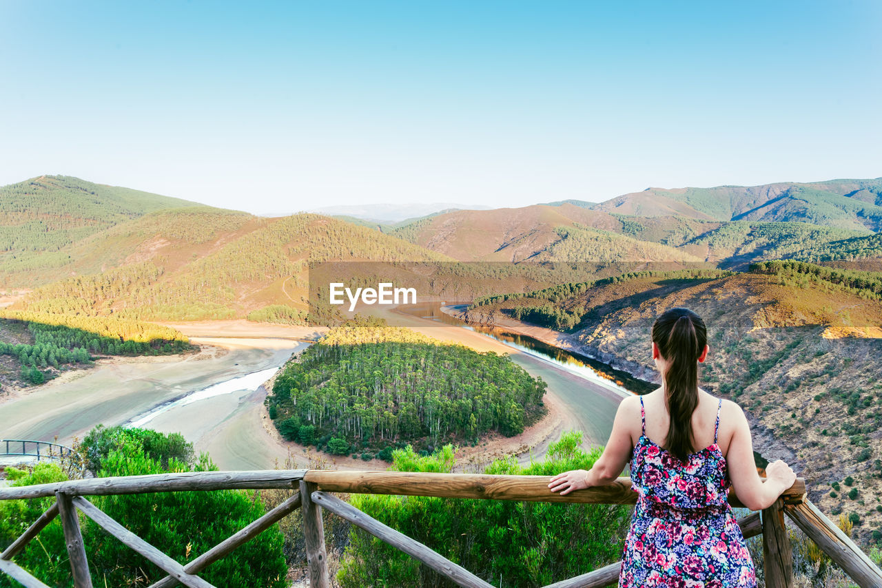 REAR VIEW OF WOMAN LOOKING AT VIEW