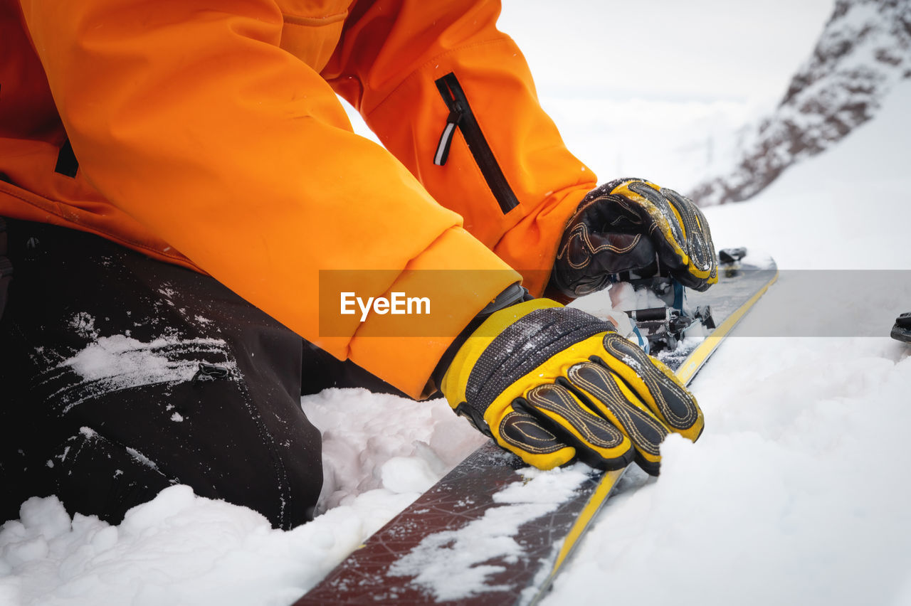 Close-up of a man's hand, adjusting the skis against the background of snow and things, putting on