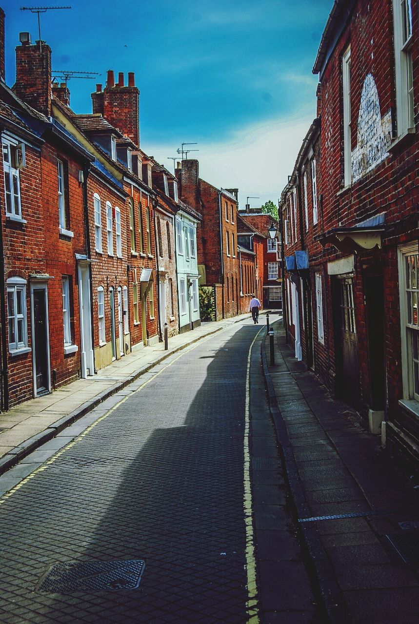 Empty cobblestone alley along buildings