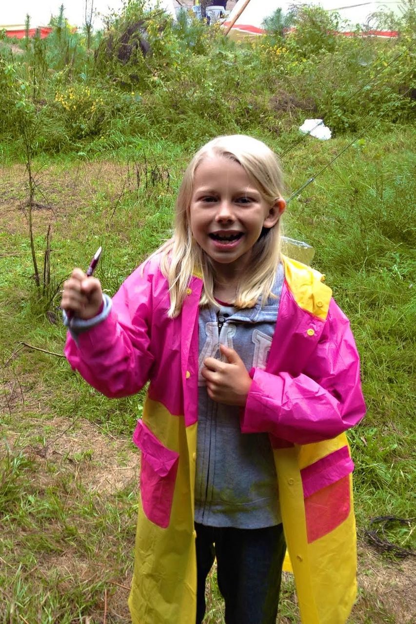 Portrait of girl with raincoat standing on field