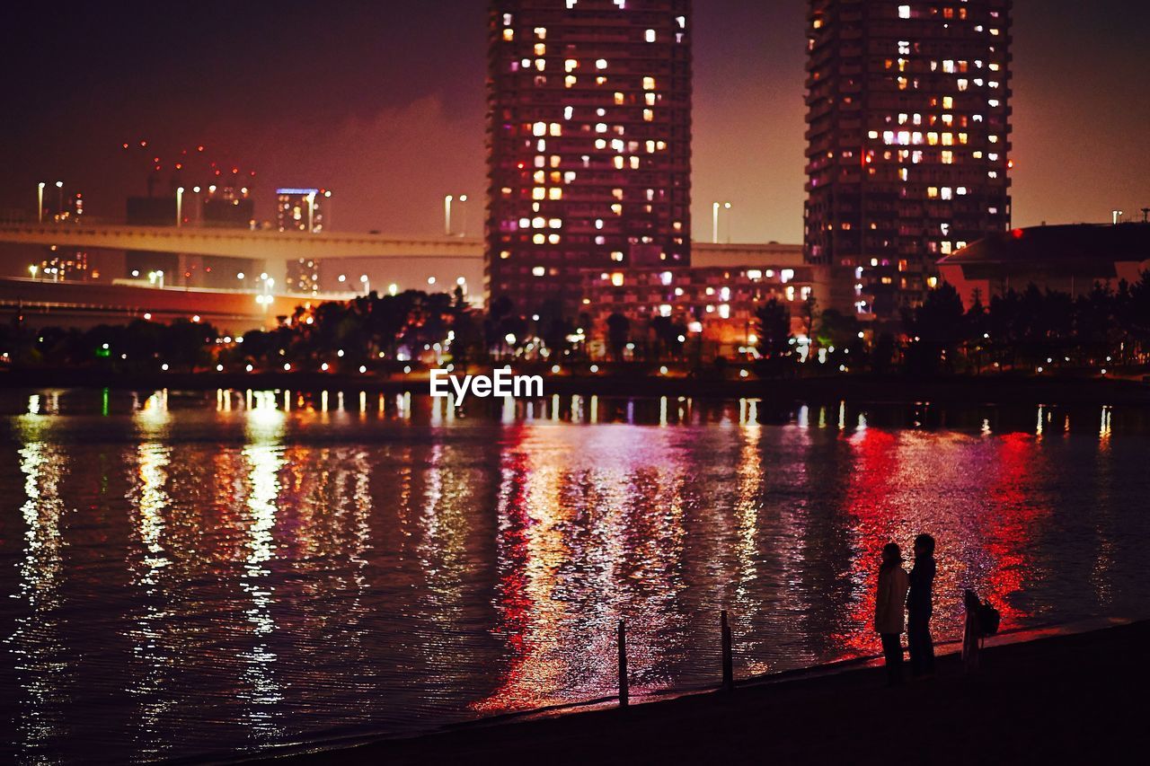 River by illuminated city at night