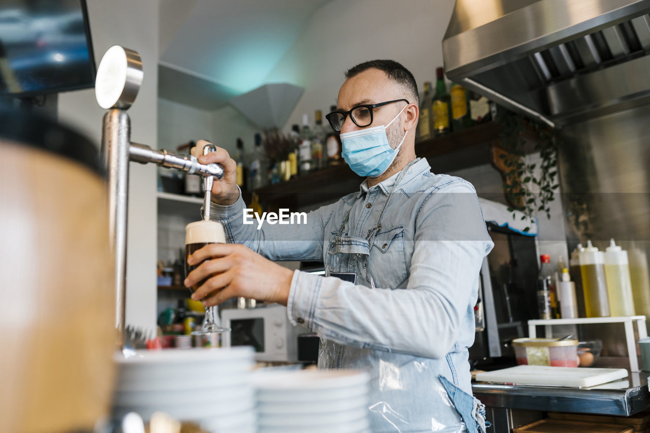 Waiter filling beer in glass in a bar during pandemic