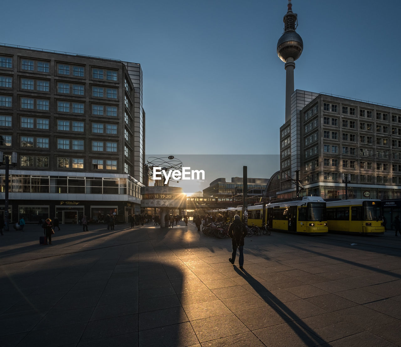 Low angle view of fernsehturm tower amidst buildings against sky during sunset