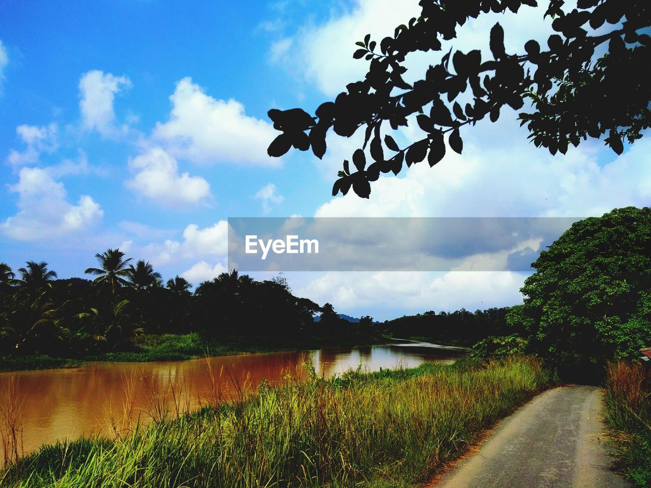 ROAD BY LAKE AGAINST SKY