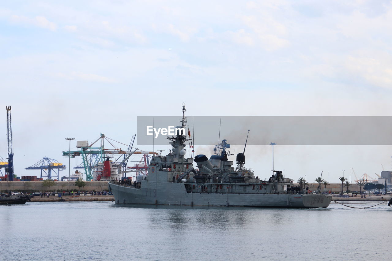 Warship at harbor against sky