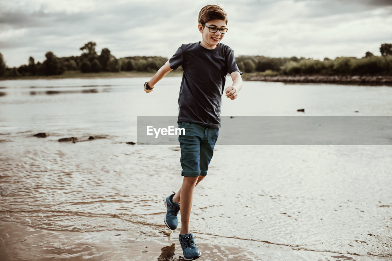 Full length of boy running on lakeshore