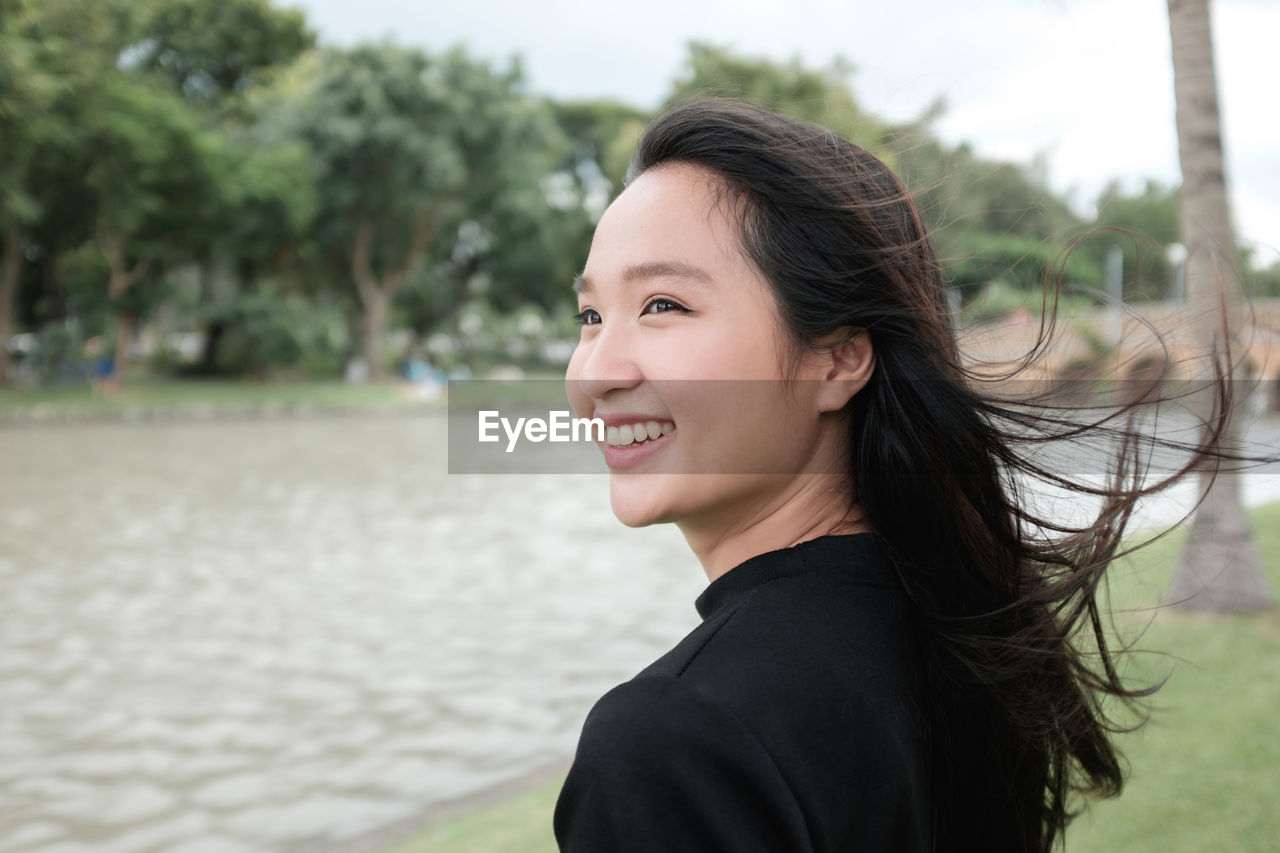 Close-up of smiling woman by lake