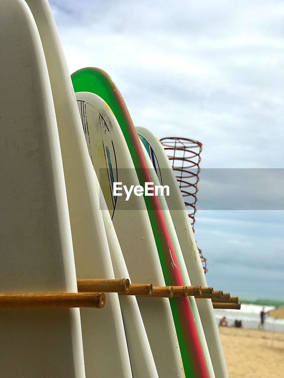 Close-up of surfboards at beach against sky