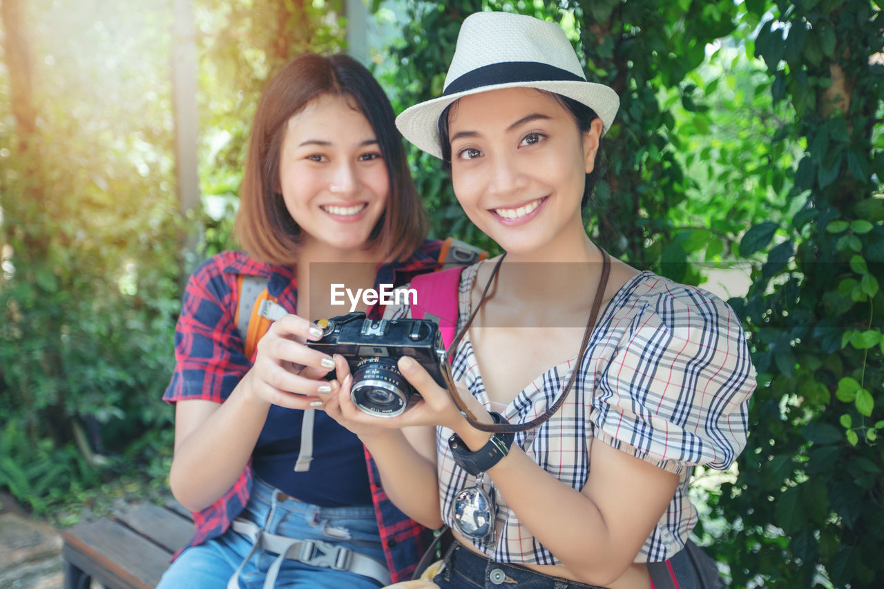 Portrait of smiling young women holding camera
