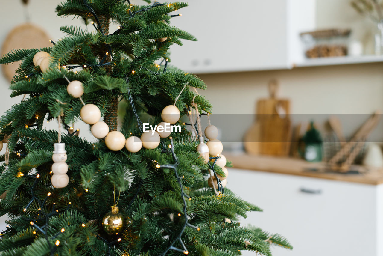 Stylish wooden beads on a christmas tree in the dining room of a scandinavian home