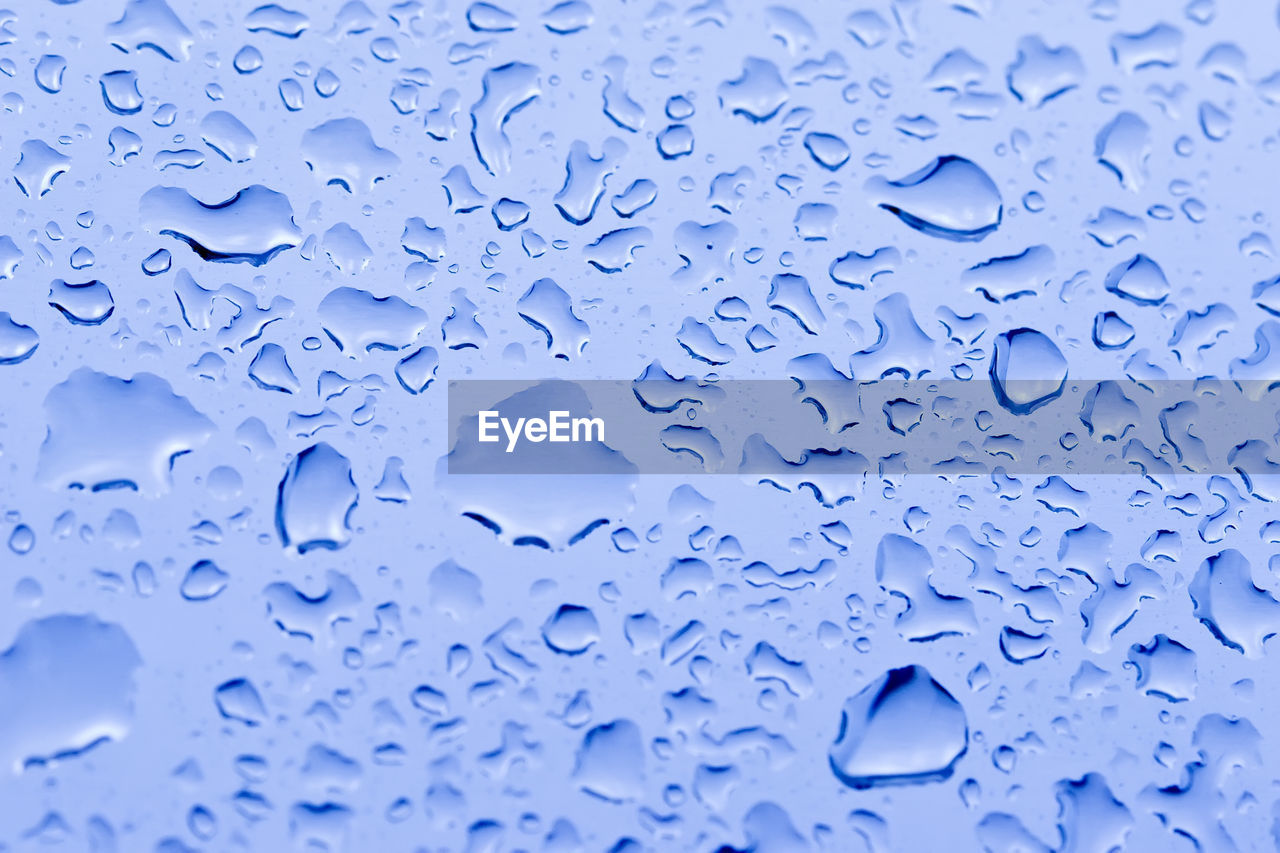 FULL FRAME SHOT OF WATER DROPS ON BLUE SURFACE