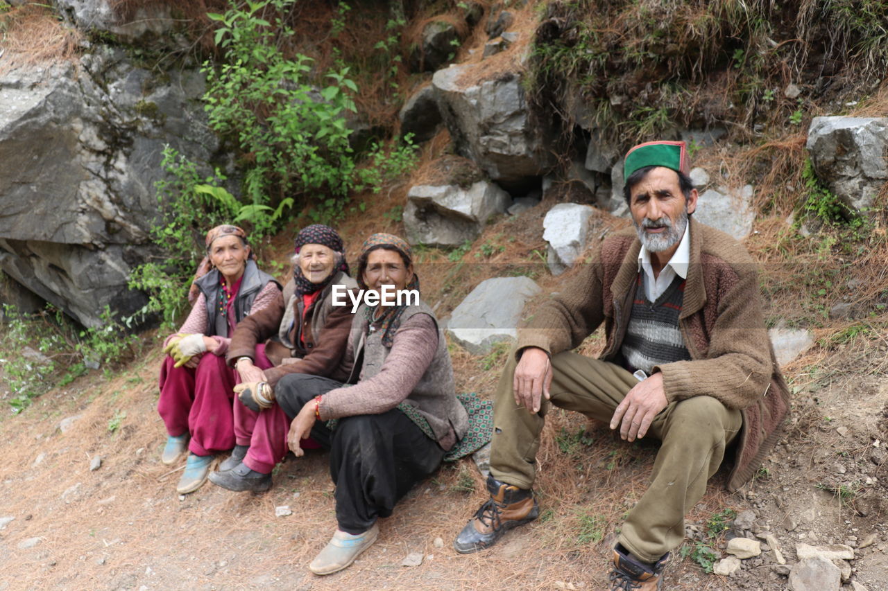 group of people, adult, sitting, men, full length, adventure, women, nature, smiling, friendship, rock, young adult, walking, wilderness, female, hiking, looking at camera, leisure activity, portrait, togetherness, emotion, happiness, geology, tree, clothing, footwear, person, relaxation, lifestyles, forest, plant, outdoors, activity, land, backpacking, front view, mature adult, hat