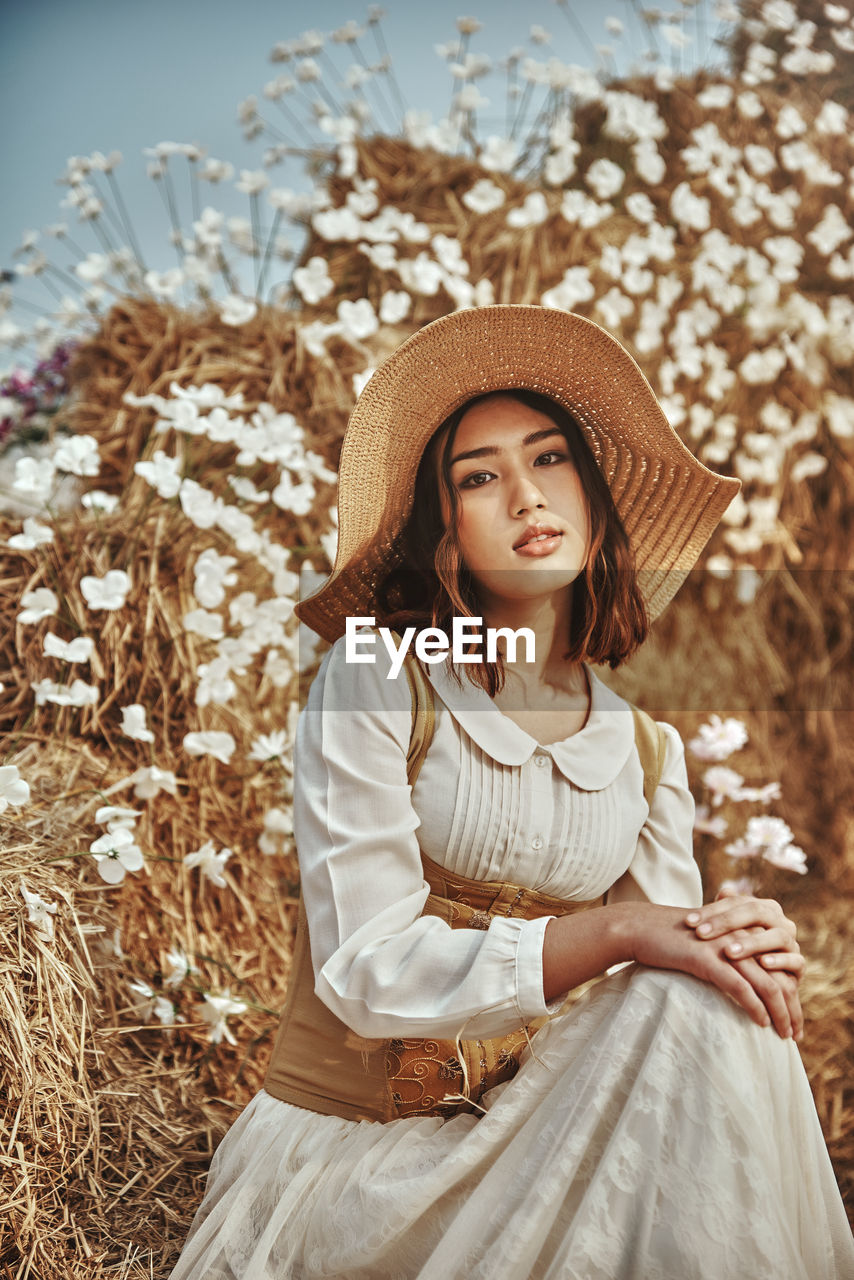 Portrait of girl wearing hat sitting against plants