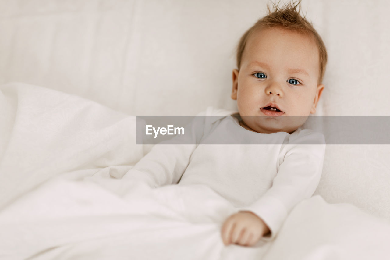 Portrait of cute baby lying on bed at home