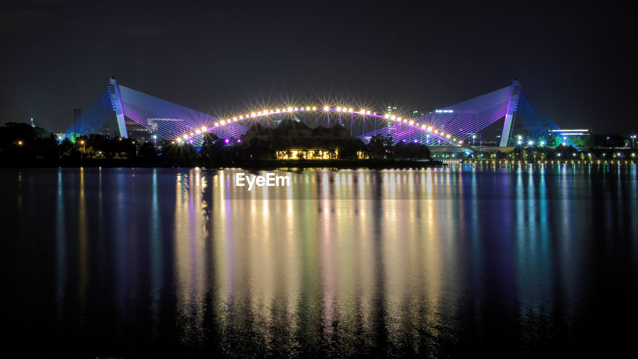 Illuminated seri saujana bridge over river against sky at night