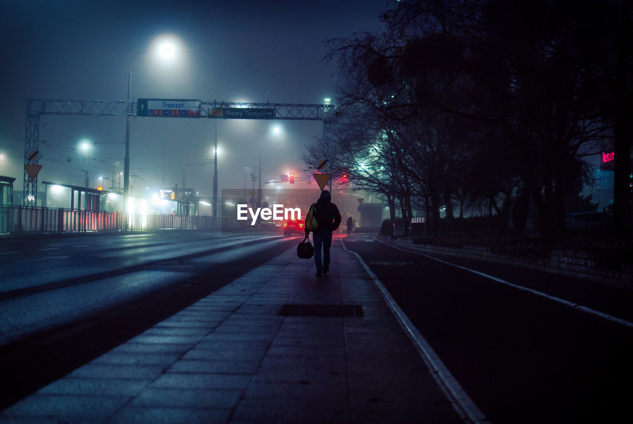 Rear view of man on road at night