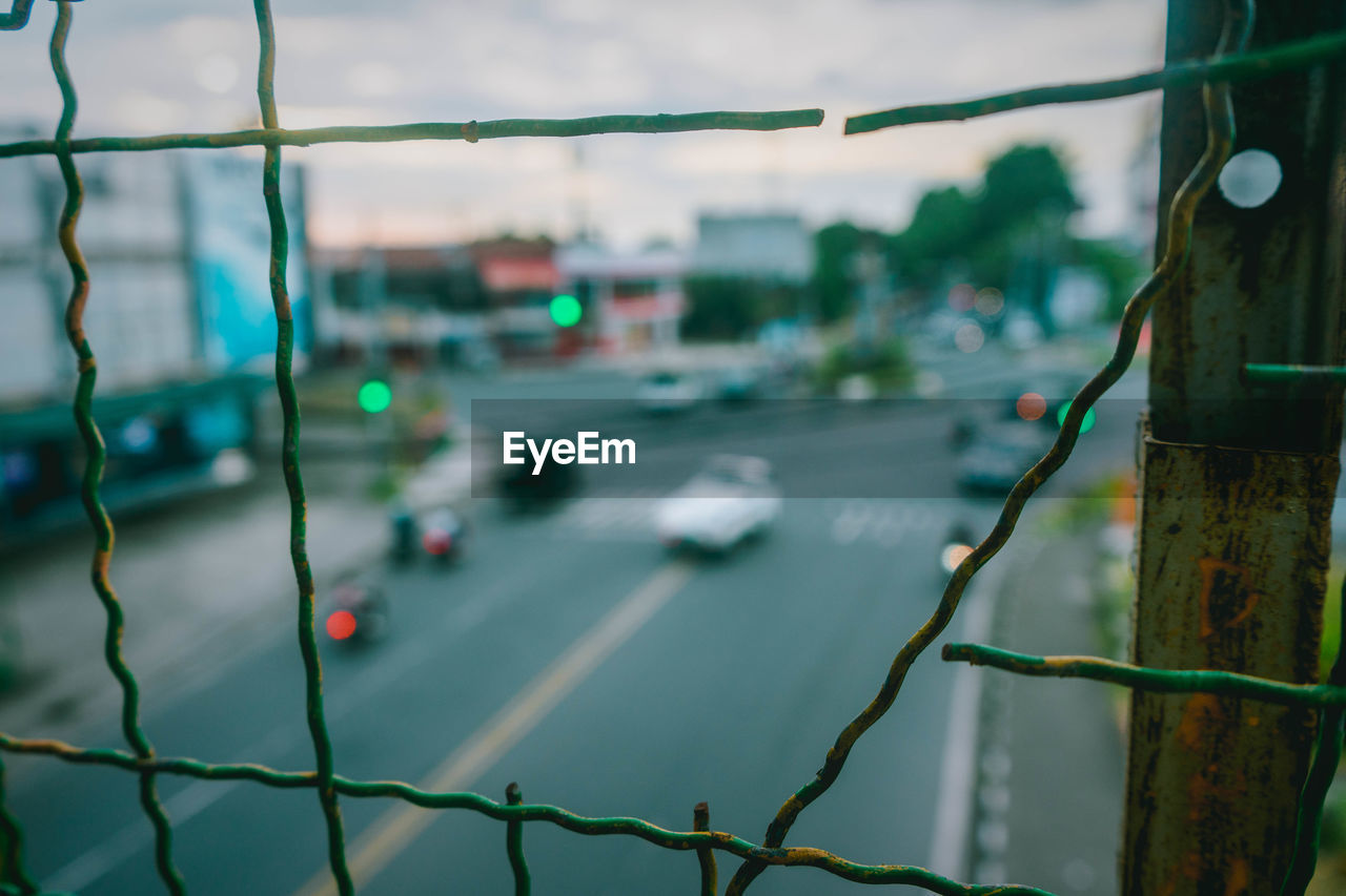 Close-up of fence by road in city