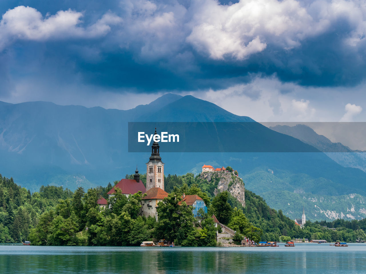 Church by lake against cloudy sky