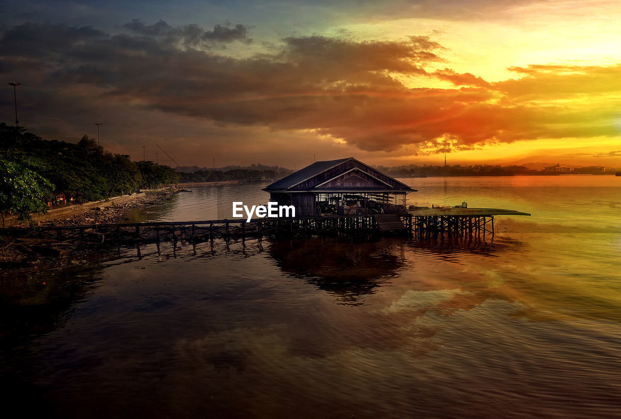 BUILT STRUCTURE ON SEA AGAINST SKY DURING SUNSET