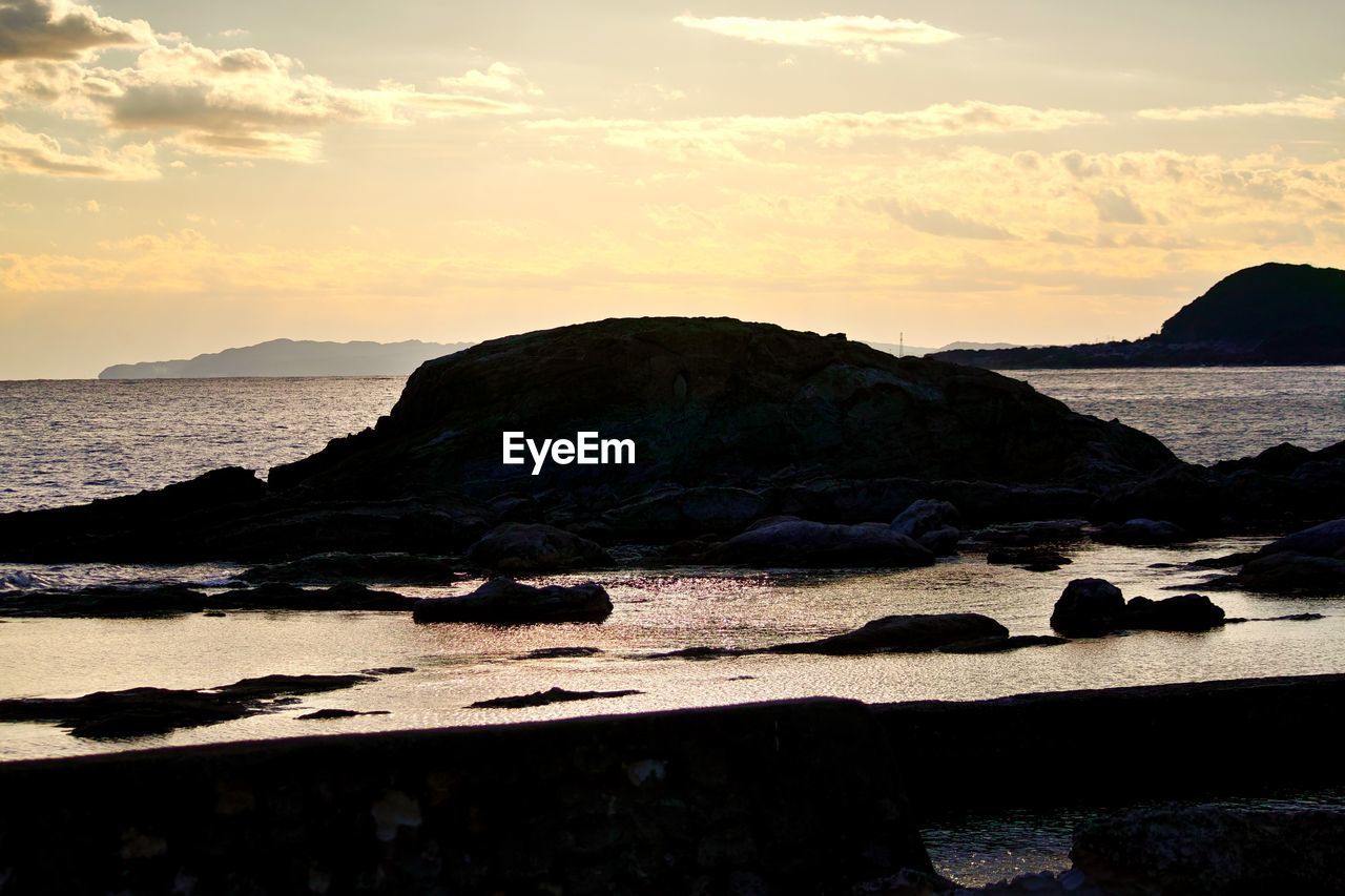 ROCK FORMATIONS ON BEACH AGAINST SKY