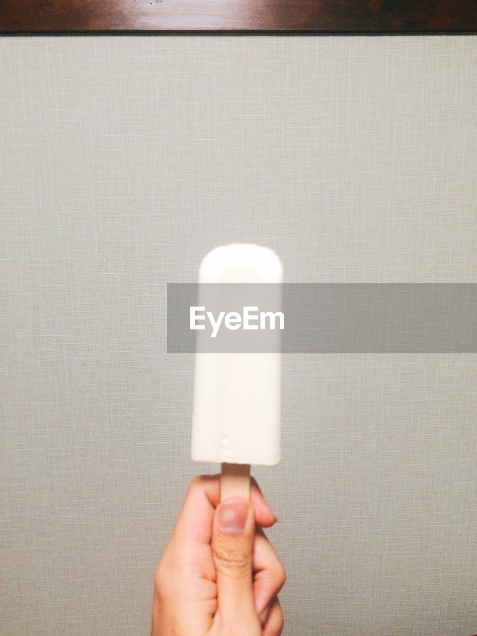 CLOSE-UP OF HAND HOLDING ICE CREAM AGAINST WHITE BACKGROUND