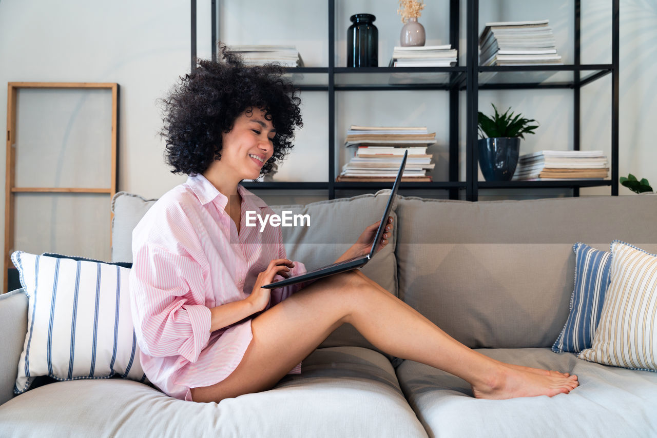 Woman using laptop on sofa at home