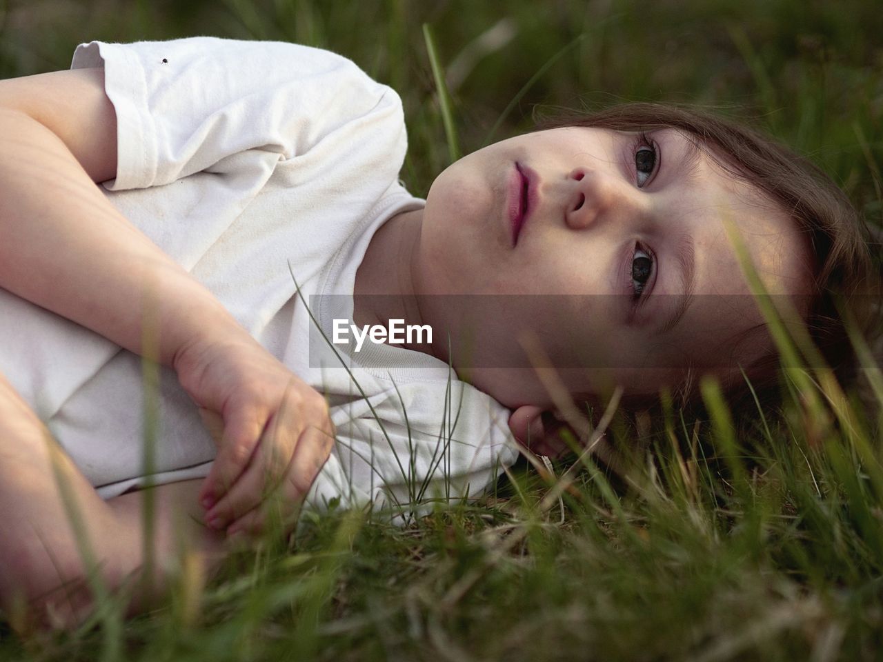Close-up of thoughtful girl lying on field