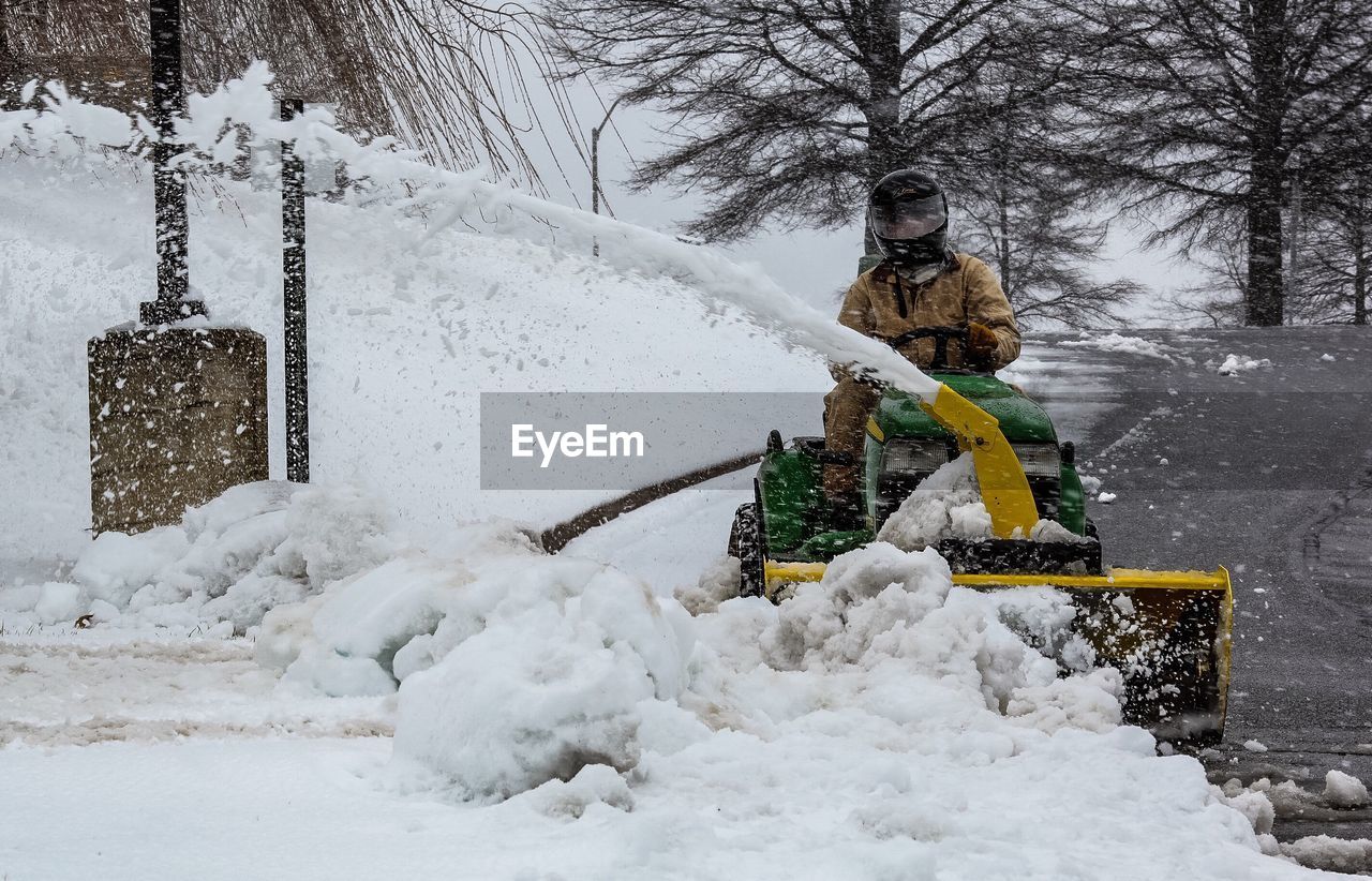 Man cleaning snow from road with snowblower