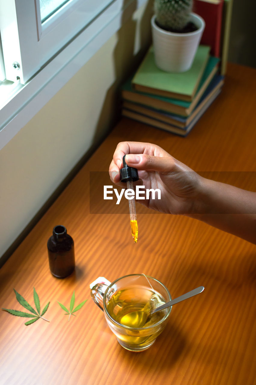 HIGH ANGLE VIEW OF PERSON PREPARING FOOD IN GLASS ON TABLE