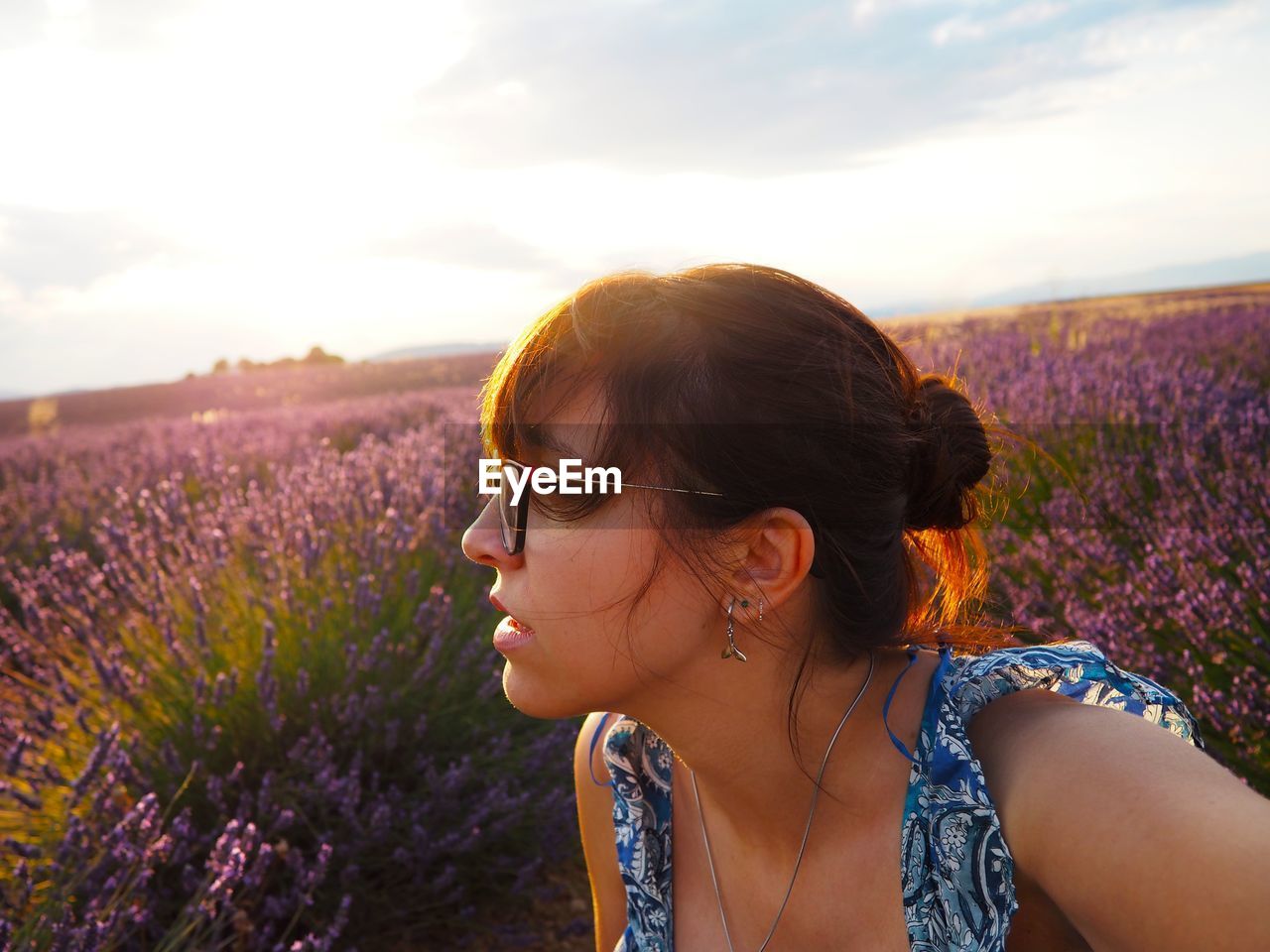 Portrait of woman with pink flowers on field against sky